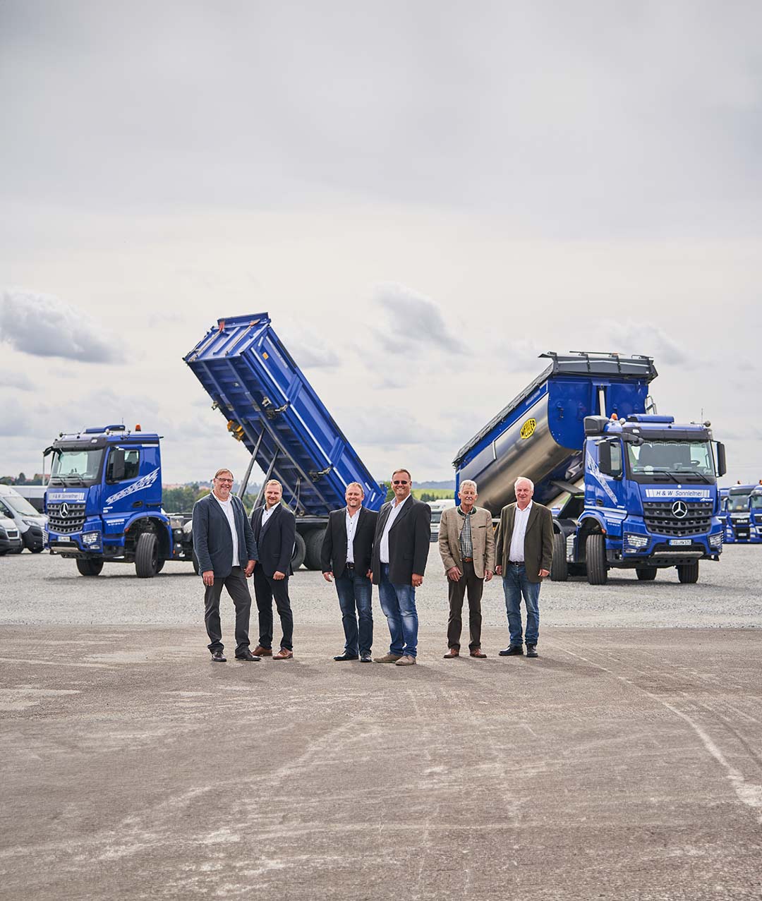 Ein älteres Bild der Geschäftsführer und führenden Mitarbeiter der ASB Group vor zwei Lastwagen