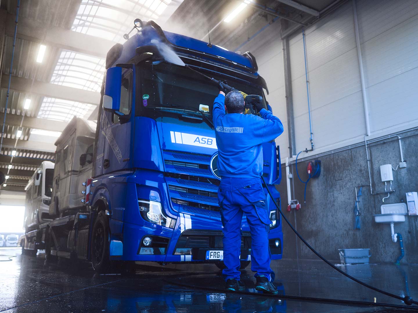 Ein Mitarbeiter der ASB Group wäscht einen LKW in der Waschstraße