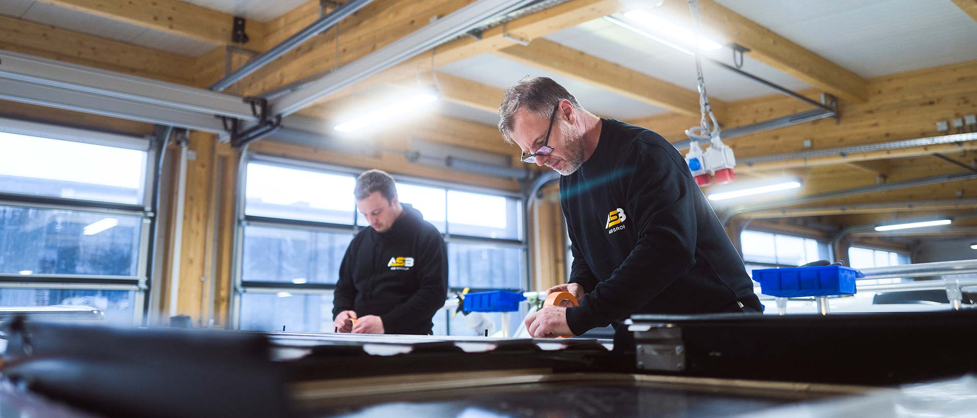 Zwei Mitarbeiter der ASB Group arbeiten am Dach eines Campingfahrzeugs