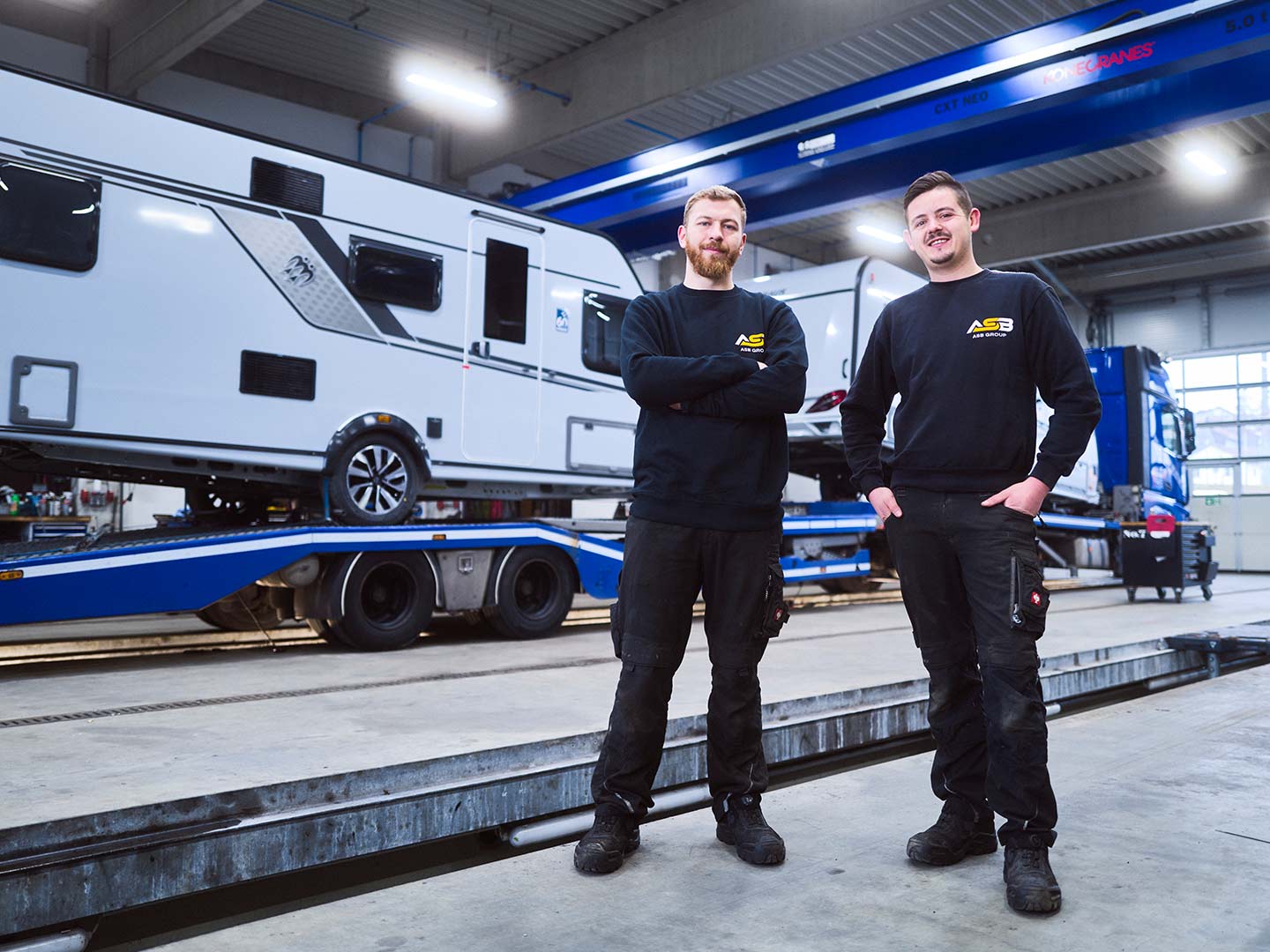 Portrait von zwei Mitarbeitern der ASB Group in einer Werkstatt-Halle