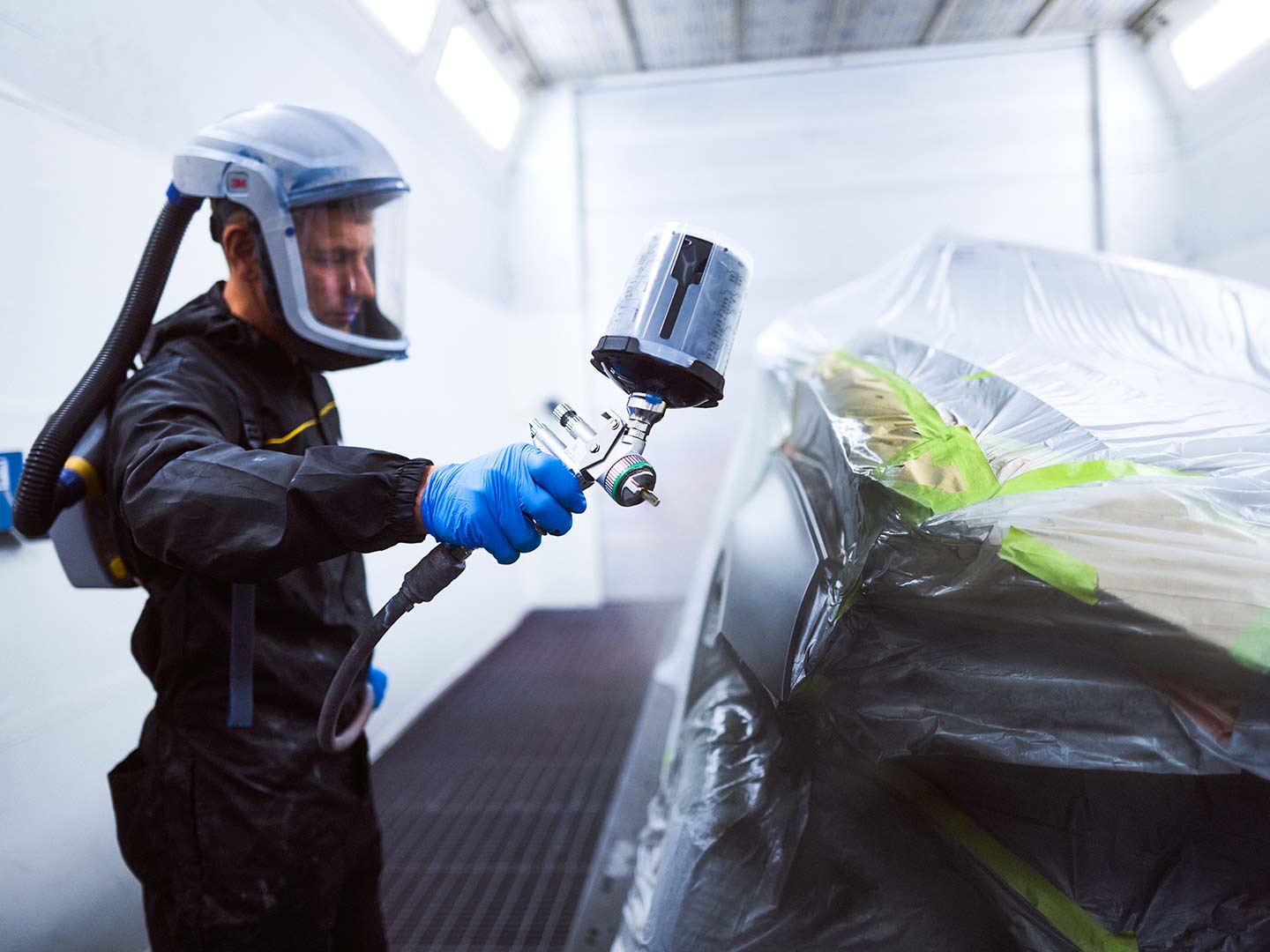 Geschäftsbereich Werkstatt und Lackierzentrum: Ein Lackierer arbeitet an einem Fahrzeug