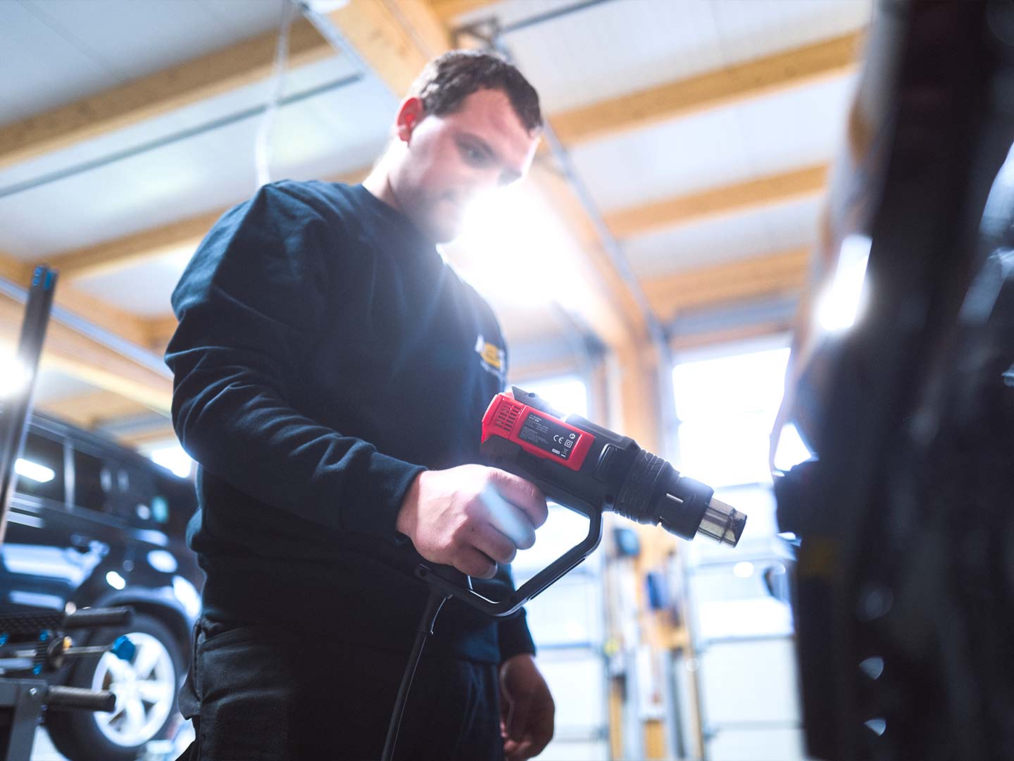 Ein Werkstattmitarbeiter der ASB Group arbeitet an einer Dellenreparatur an einem PKW