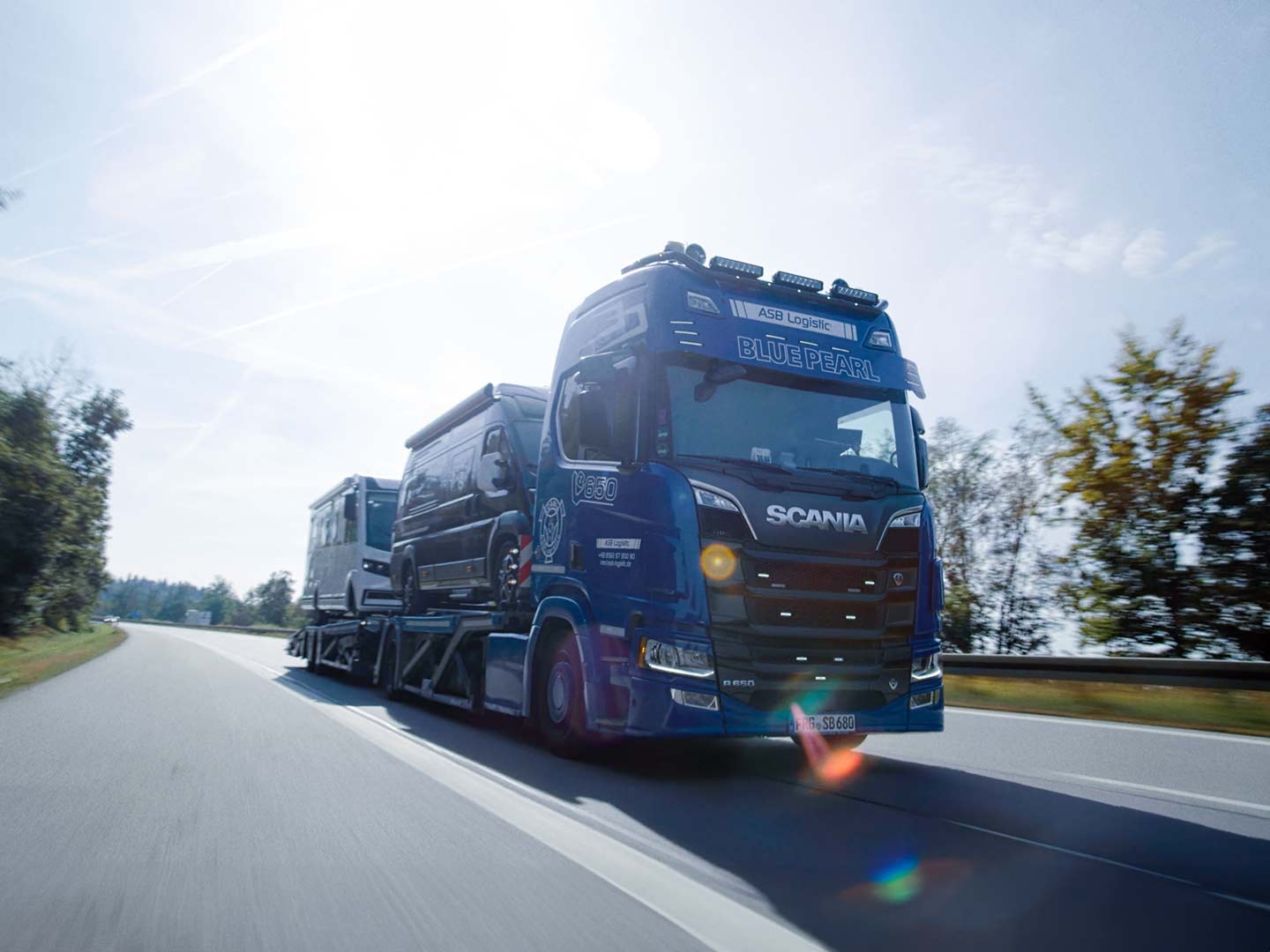 Ein LKW fährt mit Campingfahrzeugen beladen auf der Straße