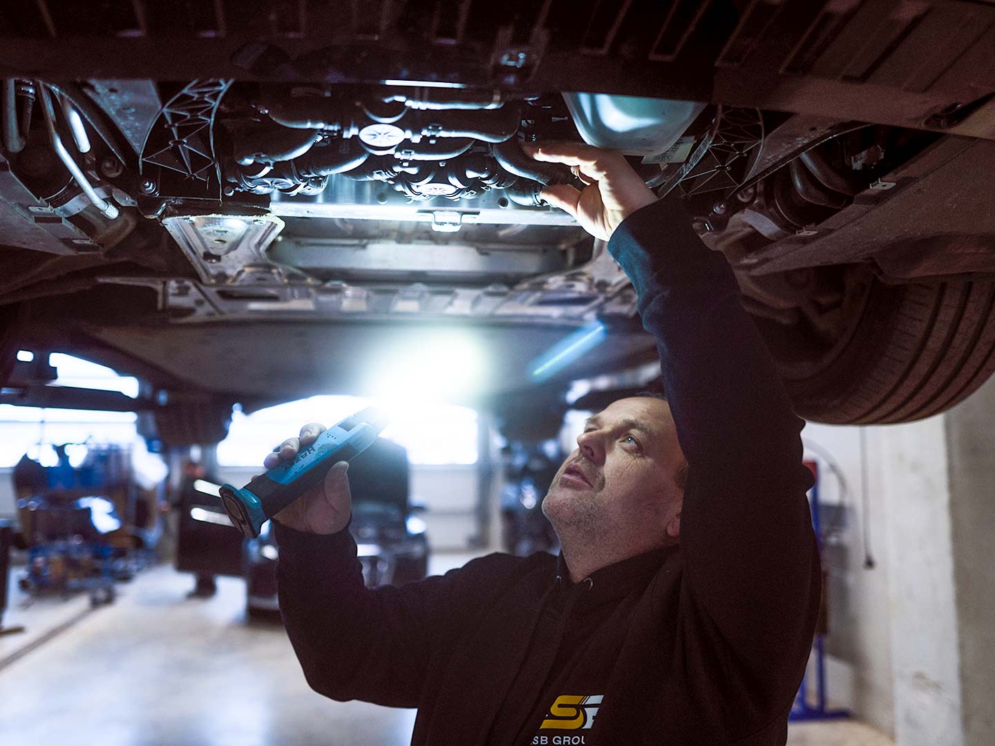 Ein Werkstattmitarbeiter der ASB Group während der Inspektion eines PKWs
