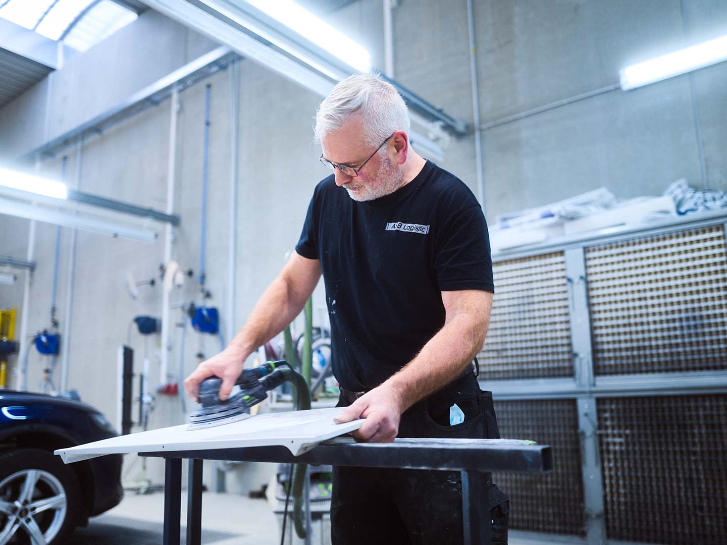 Ein Mitarbeiter der Lackiererei der ASB Group während der Vorbereitung eines PKW-Teils