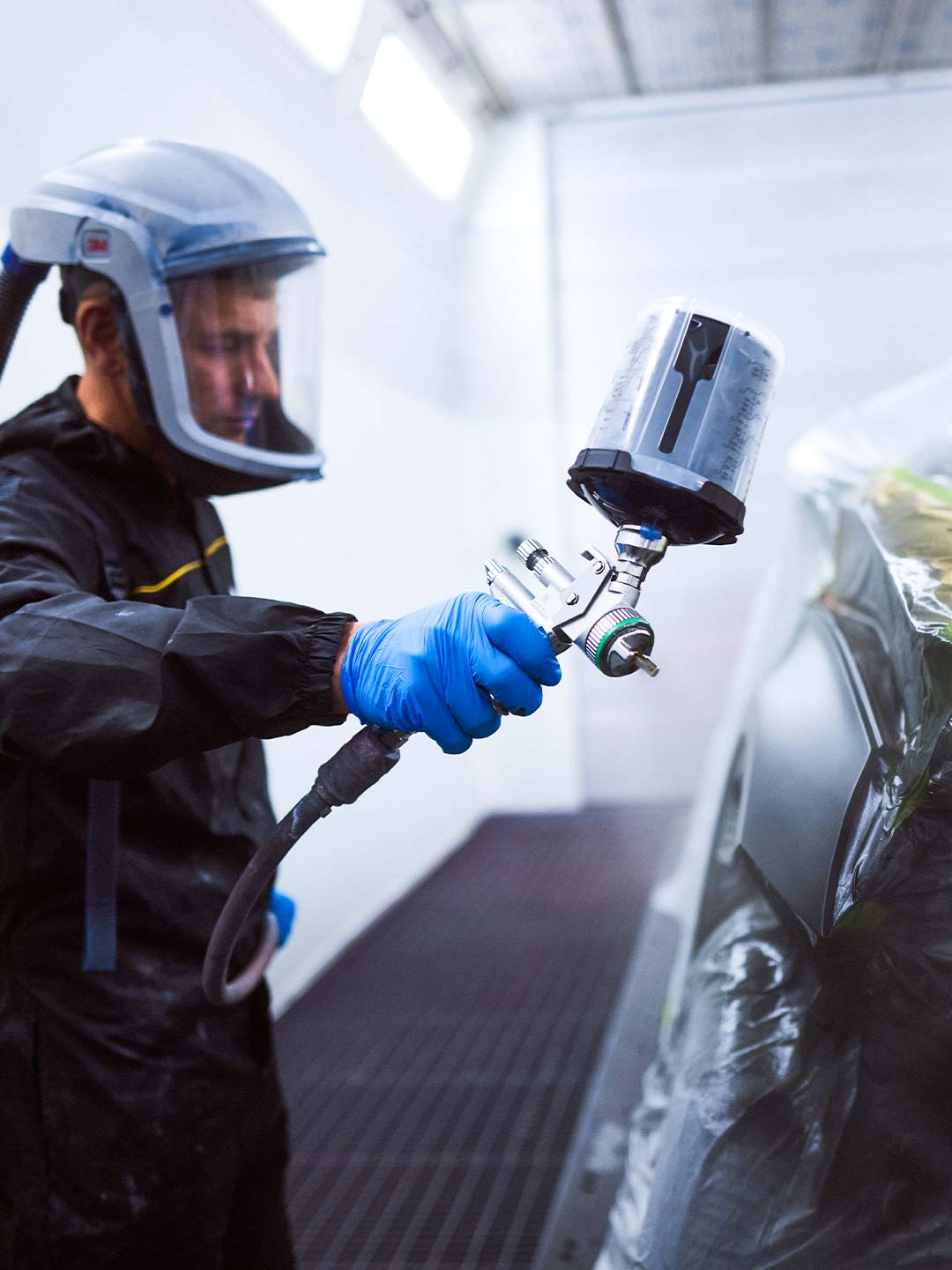 Ein Lackierer während Lackierarbeiten an einem PKW