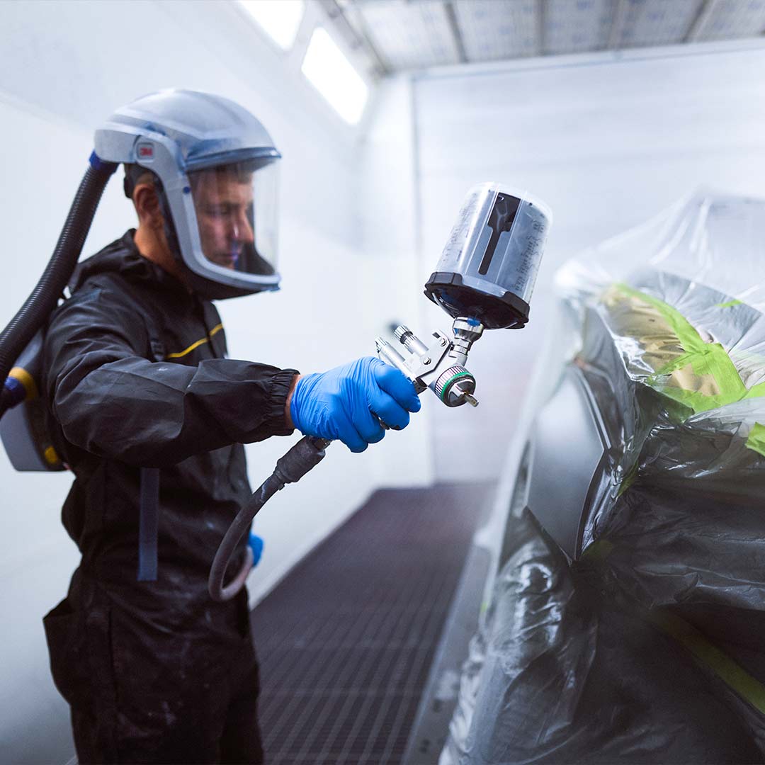 Geschäftsbereich Werkstatt und Lackierzentrum: Ein Lackierer arbeitet an einem Fahrzeug