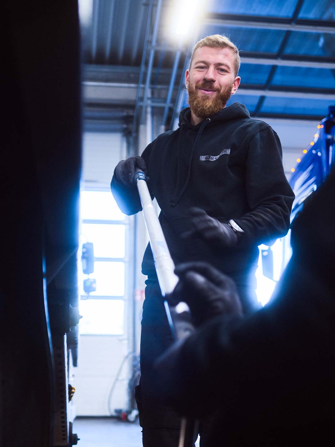 Mitarbeiter aus der LKW-Werkstatt arbeitet im Teamwork mit einem Kollegen an einem LKW