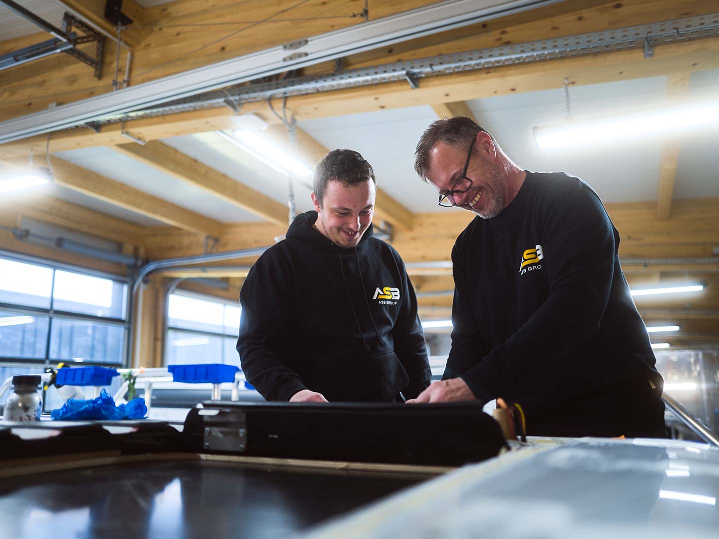 Zwei Mitarbeiter der ASB Group bearbeiten das Dach eines Campingfahrzeugs