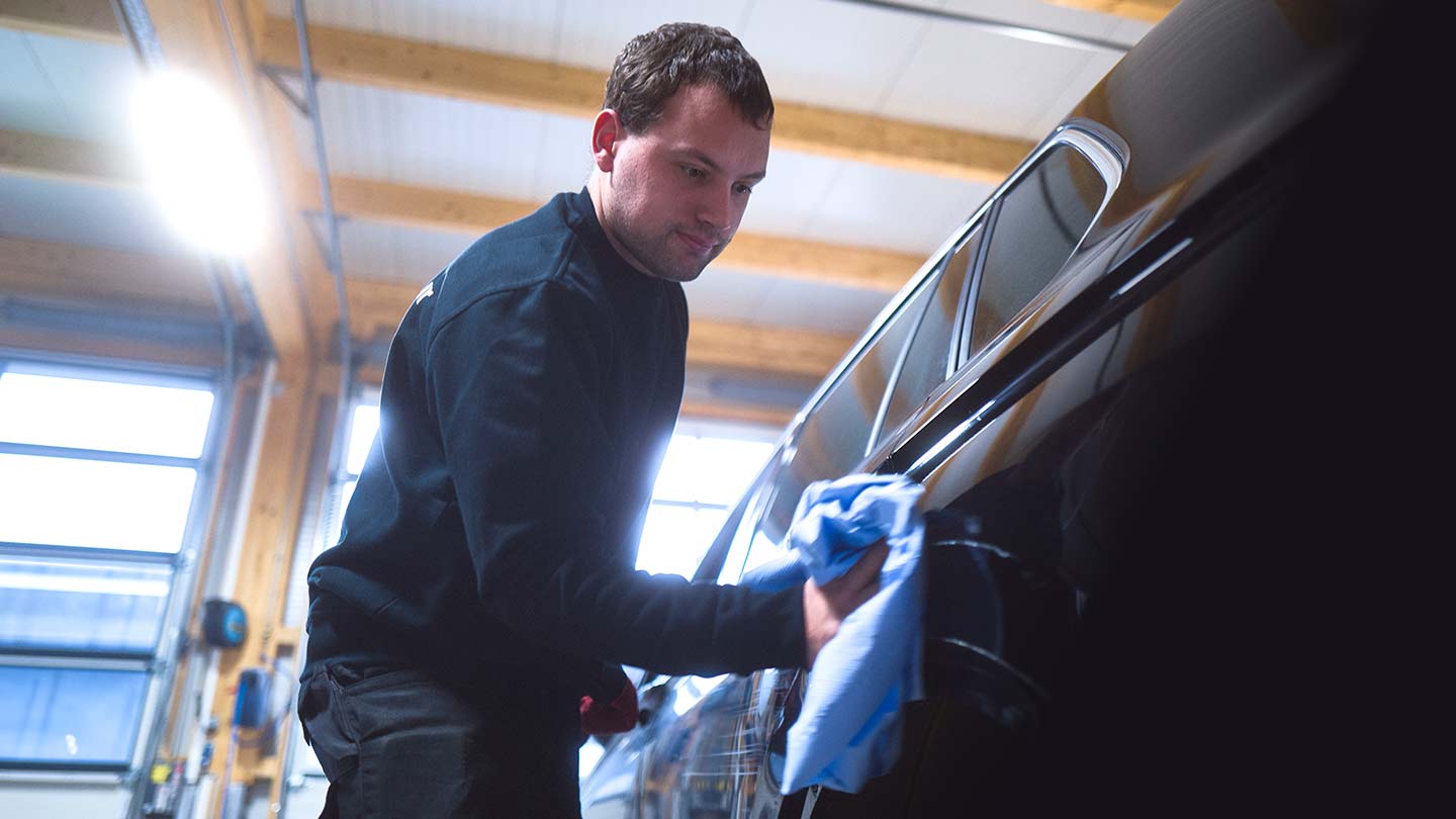 Ein Werkstattmitarbeiter der ASB Group poliert den Lack eines Fahrzeugs