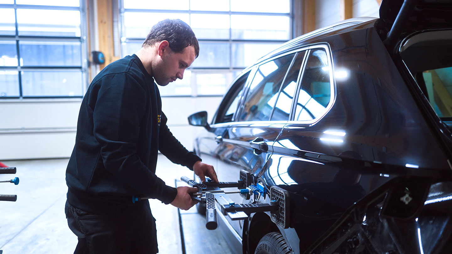 Ein Werkstattmitarbeiter der ASB Group arbeitet an einer Dellenreparatur an einem PKW
