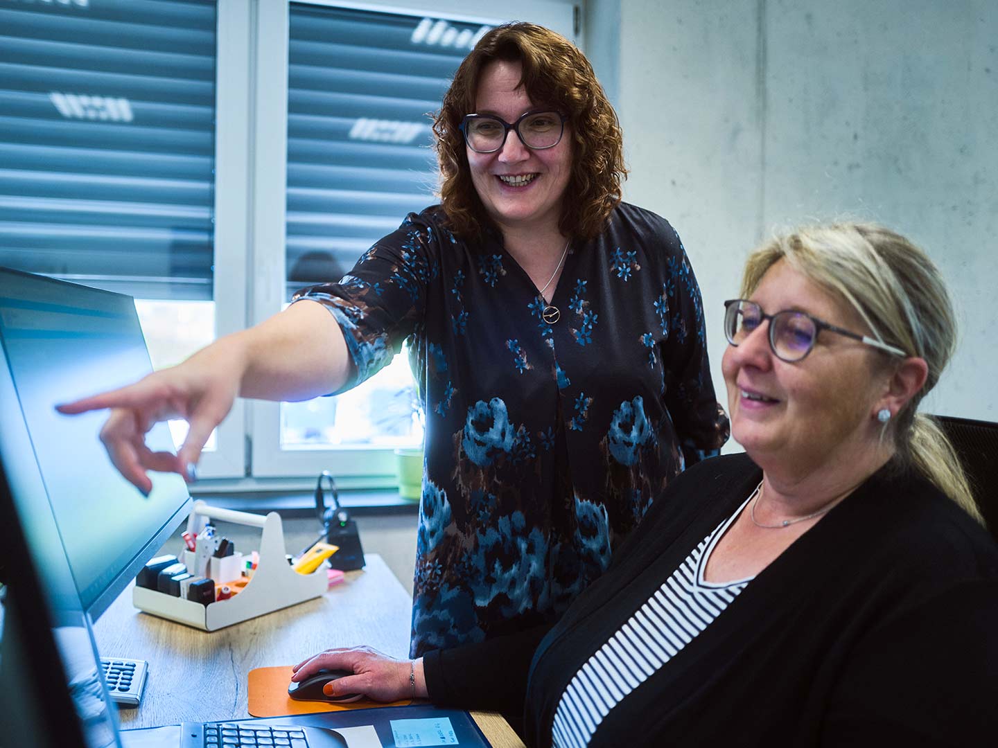 Zwei Büromitarbeiterinnen der ASB Group arbeiten gemeinsam am PC