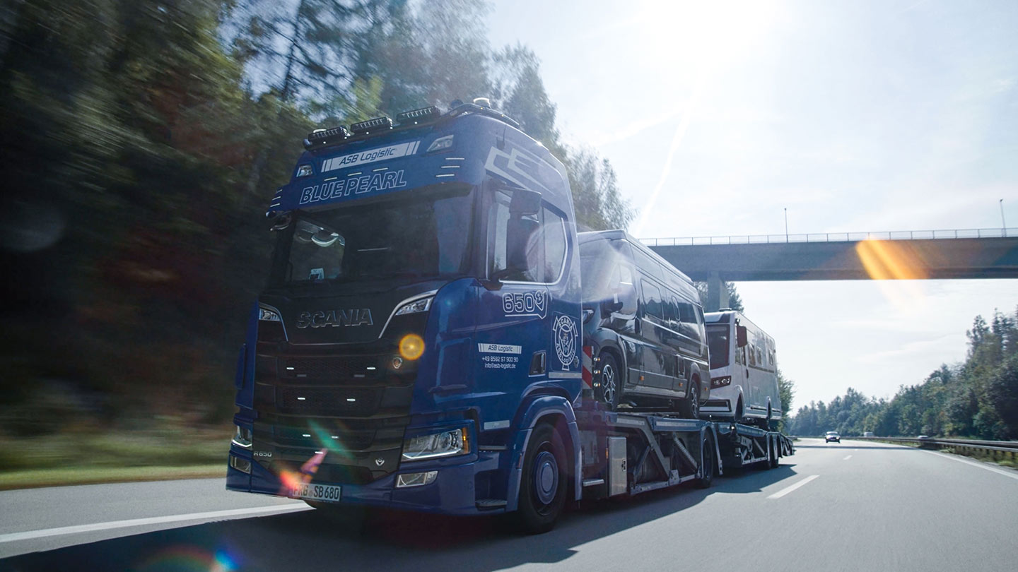 Ein LKW fährt mit Campingfahrzeugen beladen auf der Straße